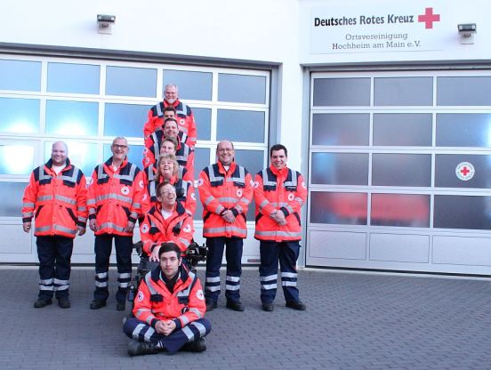 Einige Helfer bilden ein rotes Kreuz vor der Fahrzeughalle der DRK-Ortsvereinigung Hochheim am Main e.V.